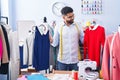 Young arab man tailor smiling confident holding t shirts at tailor shop Royalty Free Stock Photo