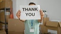 Young arab man volunteer holding thank you message over face at charity center