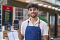 Young arab man waiter holding data phone working at restaurant