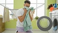 Young arab man washing clothes smelling clean towel at laundry room