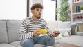 Young arab man watching television drinking coffee at home Royalty Free Stock Photo