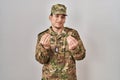 Young arab man wearing camouflage army uniform doing money gesture with hands, asking for salary payment, millionaire business