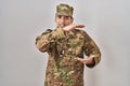 Young arab man wearing camouflage army uniform gesturing with hands showing big and large size sign, measure symbol Royalty Free Stock Photo