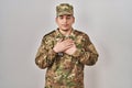 Young arab man wearing camouflage army uniform smiling with hands on chest with closed eyes and grateful gesture on face