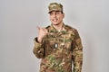 Young arab man wearing camouflage army uniform smiling with happy face looking and pointing to the side with thumb up Royalty Free Stock Photo