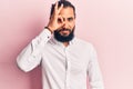 Young arab man wearing casual clothes doing ok gesture with hand smiling, eye looking through fingers with happy face Royalty Free Stock Photo