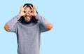 Young arab man wearing casual clothes doing ok gesture like binoculars sticking tongue out, eyes looking through fingers Royalty Free Stock Photo