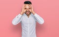 Young arab man wearing casual clothes doing ok gesture like binoculars sticking tongue out, eyes looking through fingers Royalty Free Stock Photo