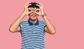 Young arab man wearing casual clothes and glasses doing ok gesture like binoculars sticking tongue out, eyes looking through Royalty Free Stock Photo