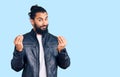 Young arab man wearing casual leather jacket doing money gesture with hands, asking for salary payment, millionaire business