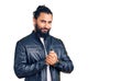 Young arab man wearing casual leather jacket with hands together and crossed fingers smiling relaxed and cheerful Royalty Free Stock Photo
