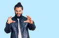 Young arab man wearing casual leather jacket smiling funny doing claw gesture as cat, aggressive and sexy expression Royalty Free Stock Photo