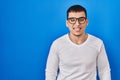 Young arab man wearing casual white shirt and glasses winking looking at the camera with sexy expression, cheerful and happy face