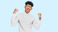 Young arab man wearing casual winter sweater very happy and excited doing winner gesture with arms raised, smiling and screaming