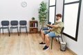 Young arab man wearing neck collar looking watch sitting on chair at hospital waiting room Royalty Free Stock Photo