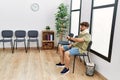 Young arab man wearing neck collar looking watch sitting on chair at hospital waiting room Royalty Free Stock Photo