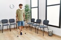 Young arab man wearing neck collar standing using crutches at hospital waiting room Royalty Free Stock Photo