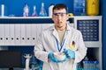 Young arab man working at scientist laboratory clueless and confused expression