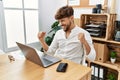 Young arab man working using computer laptop at the office very happy and excited doing winner gesture with arms raised, smiling Royalty Free Stock Photo