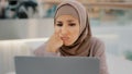 Young arab sorrowful woman in hijab reading message on laptop gets bad news denied bank loan job dismissal bankruptcy