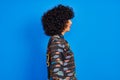 Young arab woman with curly hair wearing colorful shirt over isolated blue background looking to side, relax profile pose with Royalty Free Stock Photo