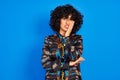 Young arab woman with curly hair wearing colorful shirt over isolated blue background thinking looking tired and bored with Royalty Free Stock Photo