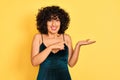Young arab woman with curly hair wearing elegant dress over isolated yellow background amazed and smiling to the camera while Royalty Free Stock Photo