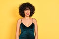 Young arab woman with curly hair wearing elegant dress over yellow background winking looking at the camera with sexy