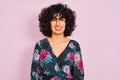 Young arab woman with curly hair wearing floral dress over isolated pink background winking looking at the camera with sexy