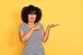 Young arab woman with curly hair wearing striped dress over isolated yellow background amazed and smiling to the camera while Royalty Free Stock Photo