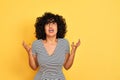 Young arab woman with curly hair wearing striped dress over isolated yellow background crazy and mad shouting and yelling with Royalty Free Stock Photo