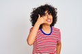 Young arab woman with curly hair wearing striped t-shirt over isolated white background smiling doing phone gesture with hand and Royalty Free Stock Photo