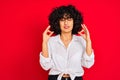 Young arab woman with curly hair wearing white casual shirt over isolated red background relax and smiling with eyes closed doing Royalty Free Stock Photo