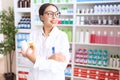 Young arab woman pharmacist holding pills bottles standing with arms crossed gesture at pharmacy Royalty Free Stock Photo