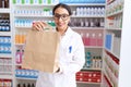 Young arab woman pharmacist smiling confident holding shopping bag at pharmacy Royalty Free Stock Photo