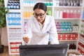 Young arab woman pharmacist using computer holding pills bottle at pharmacy Royalty Free Stock Photo