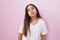 Young arab woman standing over pink background looking sleepy and tired, exhausted for fatigue and hangover, lazy eyes in the