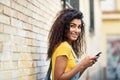 Young Arab woman texting with her smart phone on brick urban wal Royalty Free Stock Photo