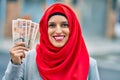 Young arab woman wearing hijab holding uk pounds at the city