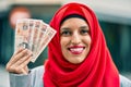 Young arab woman wearing hijab holding uk pounds at the city