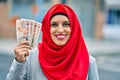 Young arab woman wearing hijab holding uk pounds at the city