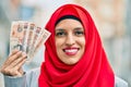 Young arab woman wearing hijab holding uk pounds at the city