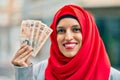 Young arab woman wearing hijab holding uk pounds at the city