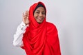 Young arab woman wearing traditional islamic hijab scarf waiving saying hello happy and smiling, friendly welcome gesture