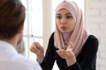 Young arabian businesswoman in hijab talking to male team leader.