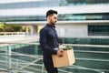 Young Arabian man with carton box leaving modern office building Royalty Free Stock Photo