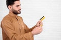 Young Arabian man keeps bitcoin and golden credit card on the white background.