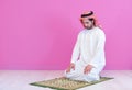 Young arabian muslim man praying on the floor at home
