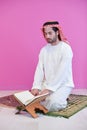 Young arabian muslim man reading Quran at home