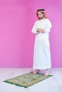 Young arabian muslim man praying on the floor at home